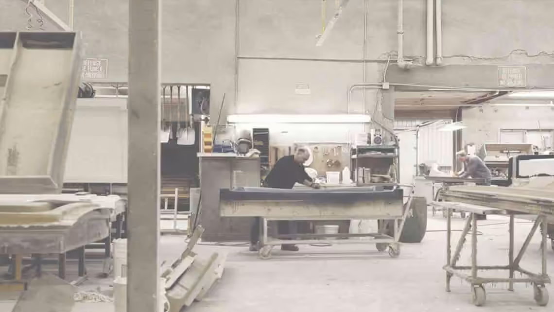 Atelier de fabrication avec deux ouvriers travaillant sur des établis et des moules industriels