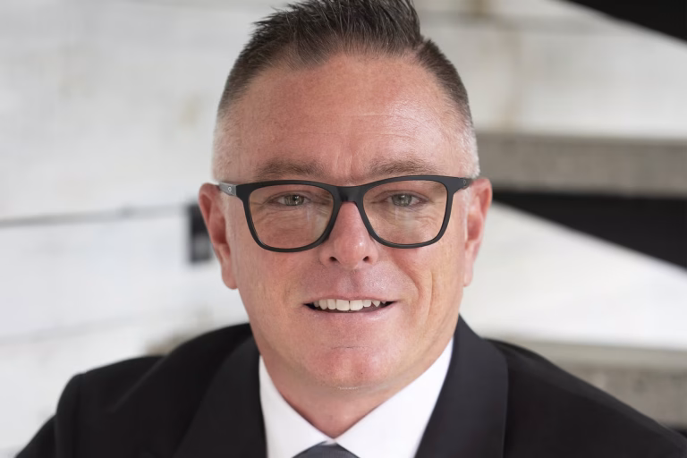 Gros plan sur le visage d’un homme portant des lunettes noires et un complet